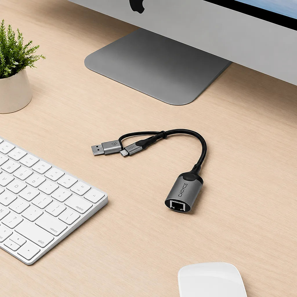 Cadyce CA-CU1000 USB-A and USB-C to RJ45 Gigabit Ethernet Adapter placed on a desktop workspace beside a keyboard and monitor -tpstech.in