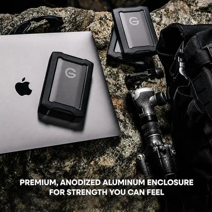 Western Digital G-DRIVE ArmorATD 6TB rugged portable external hard drive with premium anodized aluminum enclosure beside a MacBook for professional storage.